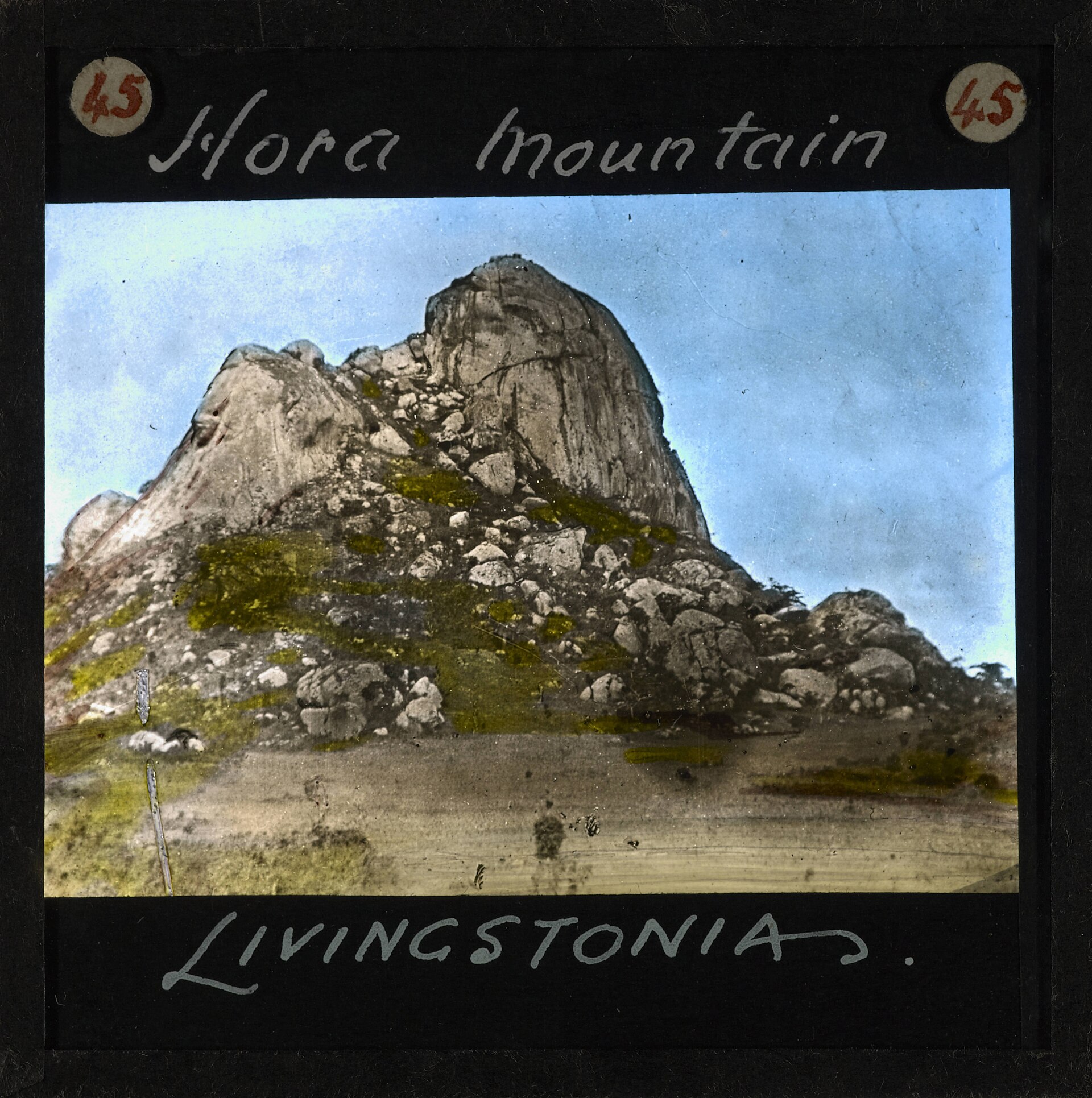 Old black-and-white photograph of a large rocky mountain rising above surrounding land