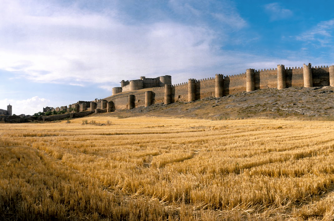 Harvested field in the foreground with a hilltop castle beyond