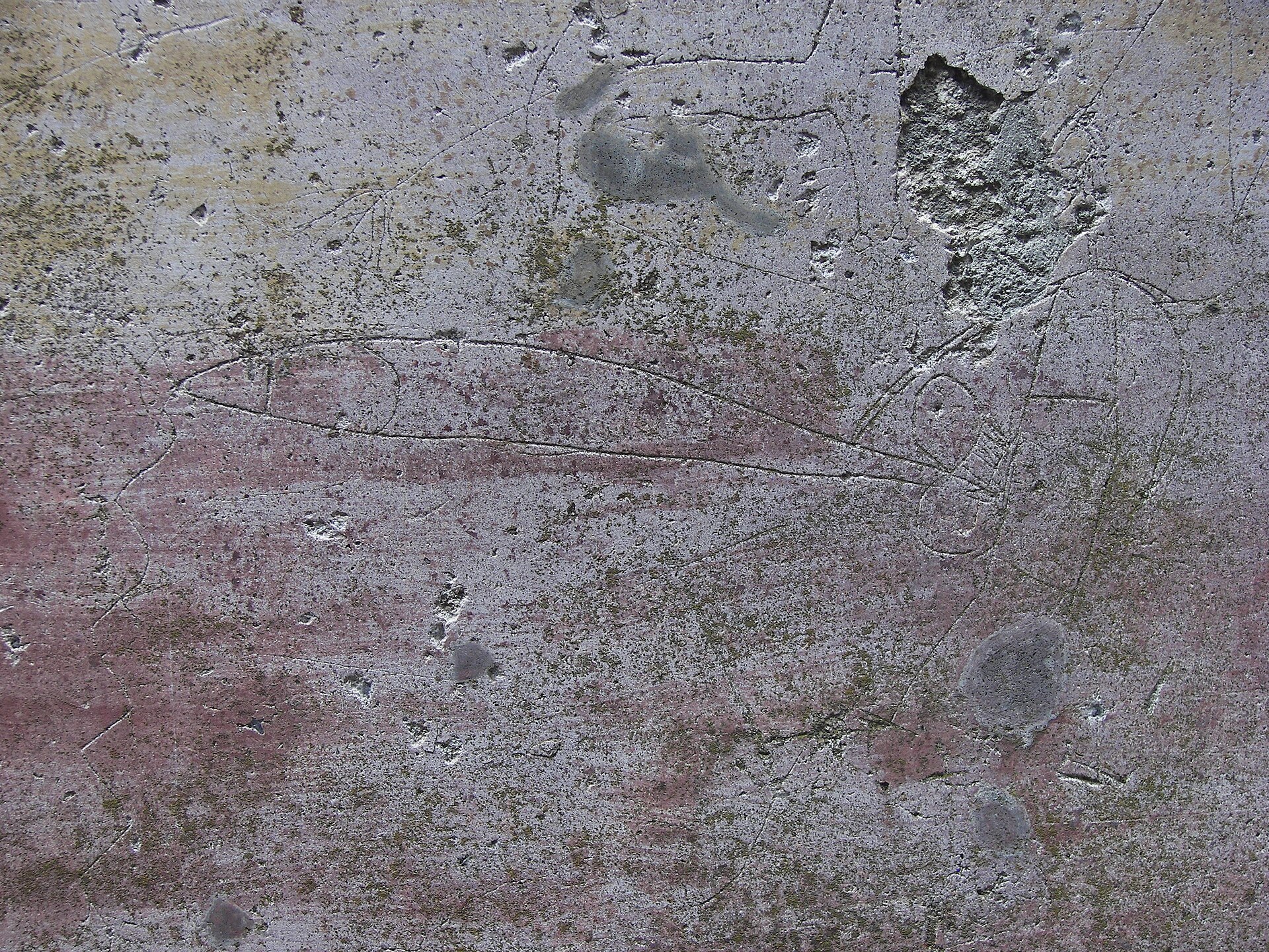 Scratched ancient inscriptions on a plaster wall in a Pompeii corridor