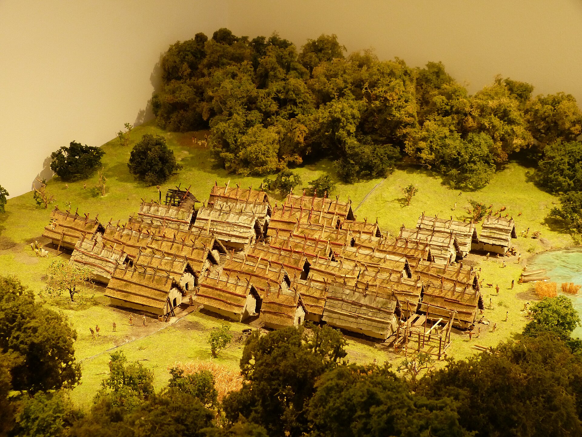 Scale model of a prehistoric village of wooden houses on a lakeshore